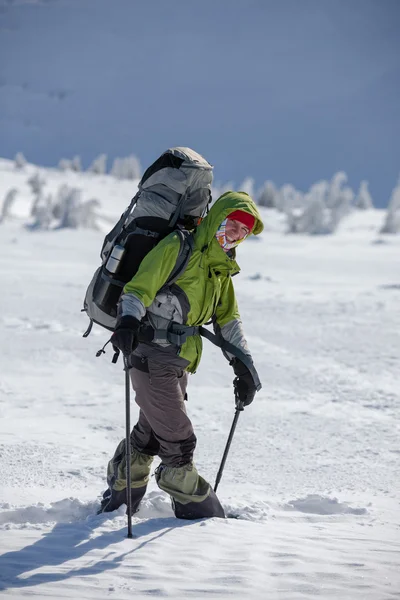 Batohem žena chodí v zimních horách na slunečný den — Stock fotografie