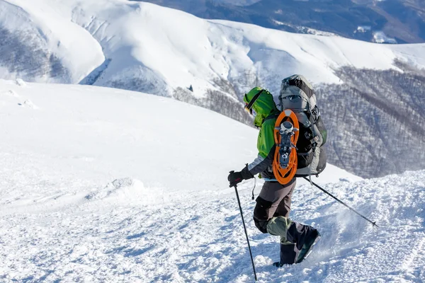 Backpacker vrouw loopt in winter bergen op zonnige dag — Stockfoto