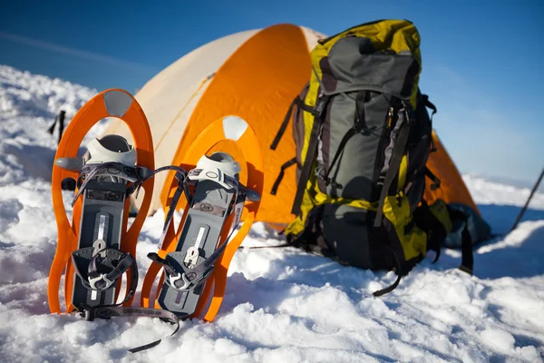 Snowshoes left in front of orange tent in winter forest — Stock Photo, Image