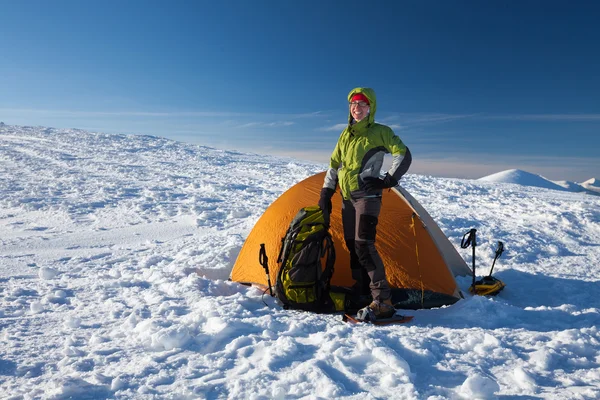 Frau posiert an sonnigem Tag vor orangefarbenem Zelt in den Winterbergen — Stockfoto