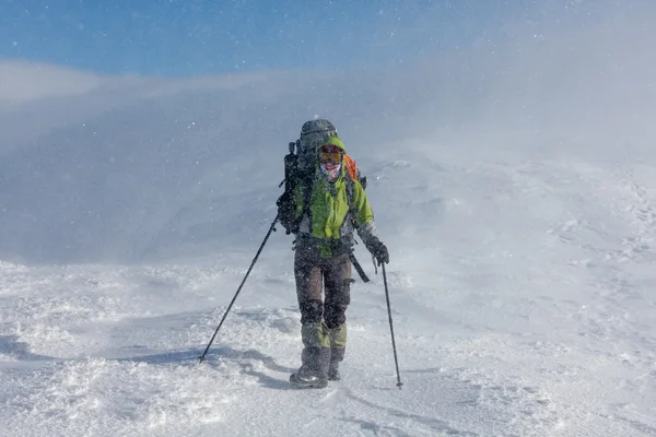 バックパッカーの女性は晴れた日に冬の山の中歩いています。 — ストック写真