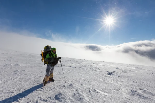 Mochilero hombre está posando en las montañas de invierno — Foto de Stock