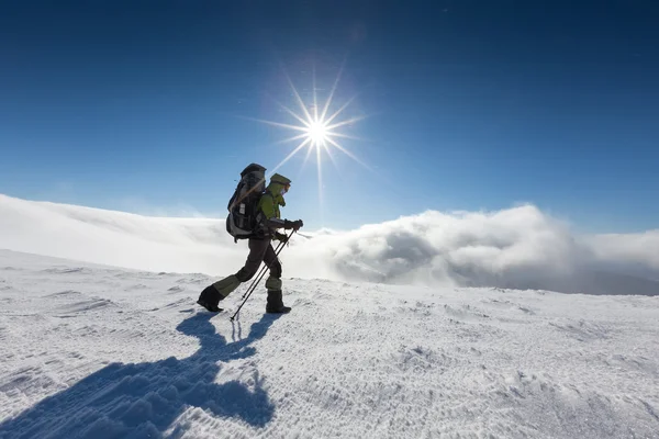 Backpacker vrouw loopt in winter bergen op zonnige dag — Stockfoto