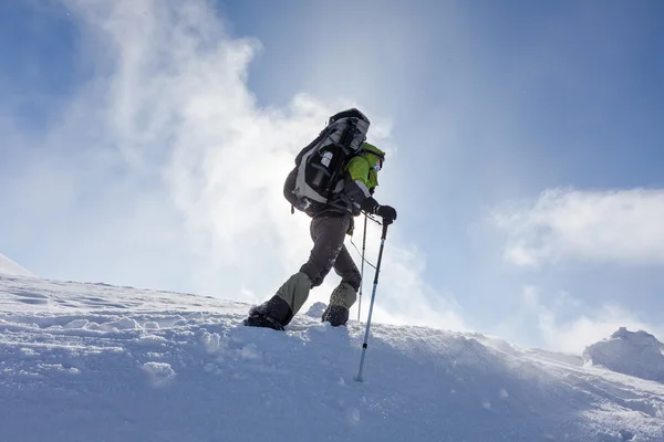 バックパッカーの女性は晴れた日に冬の山の中歩いています。 — ストック写真