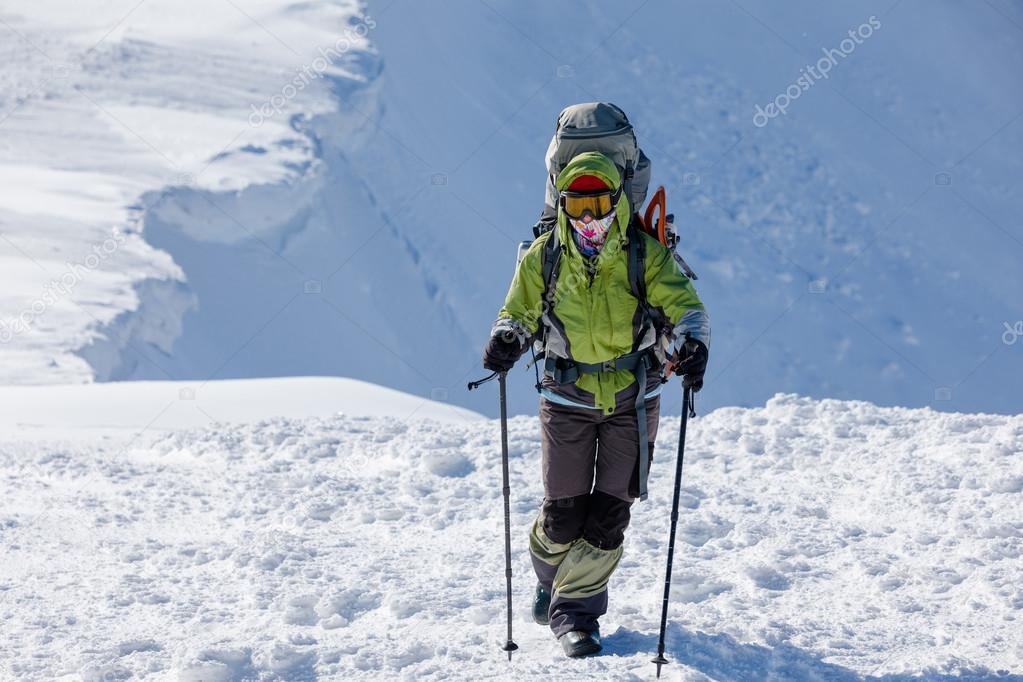 Backpacker woman is walking in winter mountains on sunny day