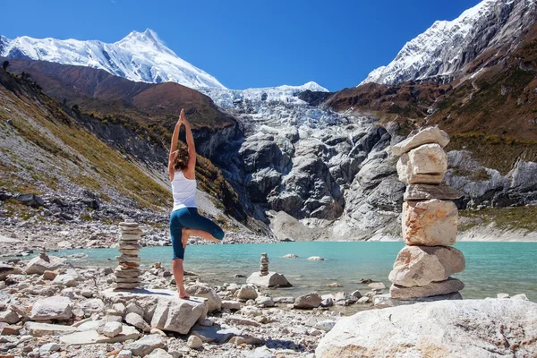 Mujer joven está practicando yoga en el lago de montaña — Foto de Stock