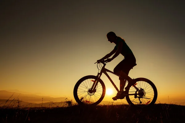 Biker-Mädchen beim Sonnenuntergang in den Bergen — Stockfoto