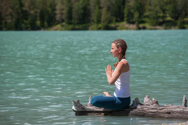 Ung kvinna utövar yoga på fjällsjö — Stockfoto