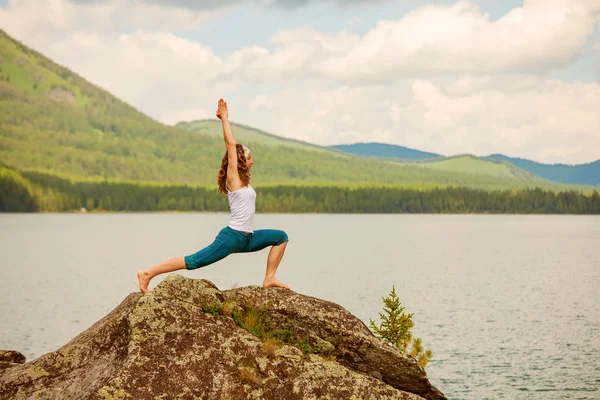 Mujer joven está practicando yoga en el lago de montaña — Foto de Stock