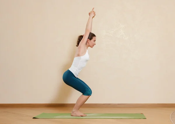 Femme caucasienne pratique le yoga en studio (utkatasana ) — Photo