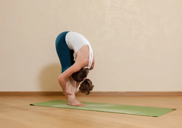Femme caucasienne pratique le yoga en studio (padahastasana ) — Photo