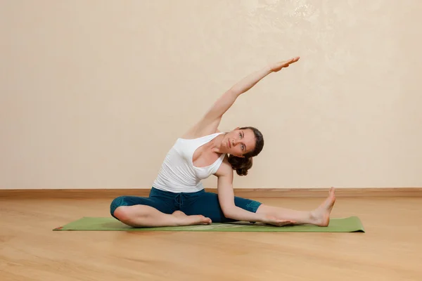 Caucasian woman is practicing yoga at studio (parivrtta janu sir — Stock Photo, Image