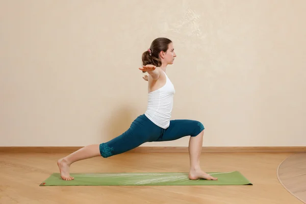 Caucasian woman is practicing yoga at studio (virabkhadrasana) — Stock Photo, Image