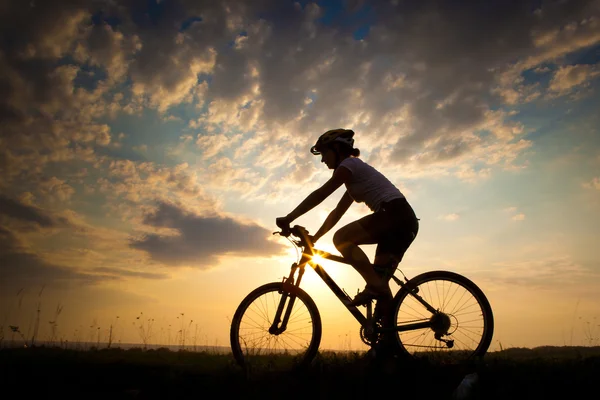 Biker-Mädchen bei Sonnenuntergang auf der Wiese — Stockfoto