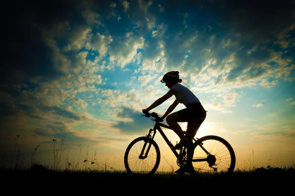 Biker-Mädchen bei Sonnenuntergang auf der Wiese — Stockfoto