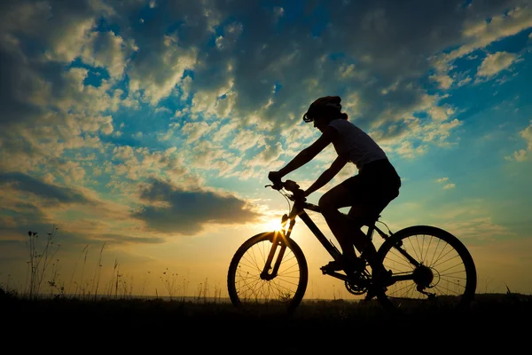 Biker-Mädchen bei Sonnenuntergang auf der Wiese — Stockfoto