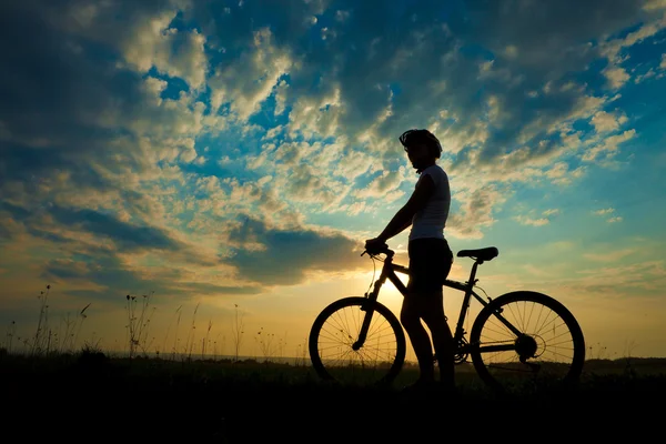 Biker-Mädchen bei Sonnenuntergang auf der Wiese — Stockfoto