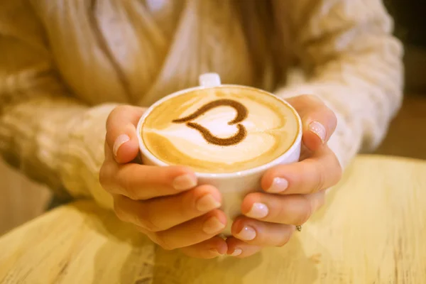 Kobieta trzyma filiżankę gorącej kawy, w kształcie serca — Zdjęcie stockowe