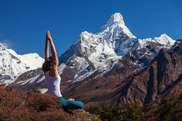 Mujer joven está practicando yoga contra las montañas del Himalaya — Foto de Stock