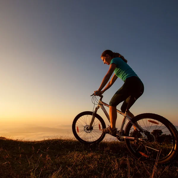 Biker-girl at the sunset on mountains — Stock Photo, Image