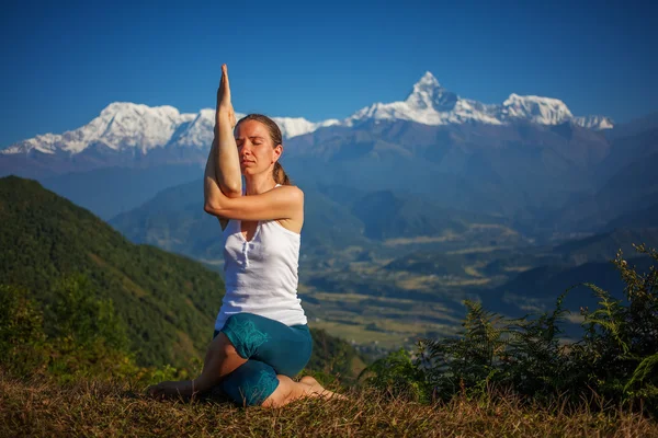 Ung kvinna utövar yoga mot Himalaya bergen — Stockfoto