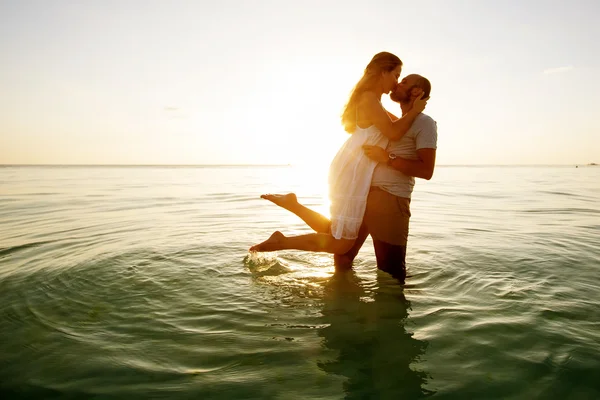 Casal romântico na praia ao pôr do sol colorido no fundo — Fotografia de Stock