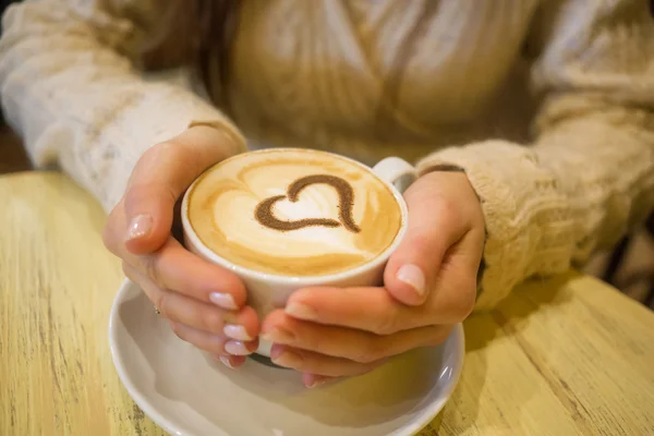 Femme tenant tasse chaude de café, avec la forme du cœur — Photo