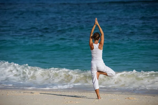 练瑜伽在海滨的白种女人 图库照片