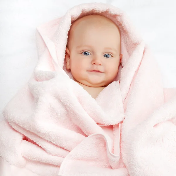 Caucasian baby boy covered with pink towel joyfully smiles at ca — Stock Photo, Image