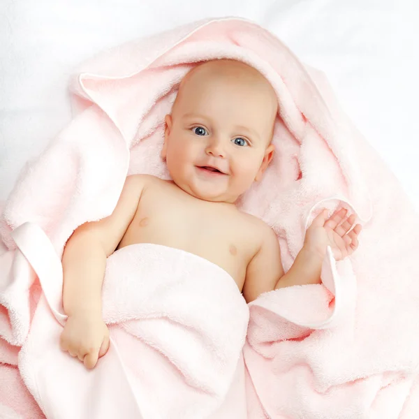 Niño caucásico cubierto con toalla rosa sonríe alegremente a ca — Foto de Stock