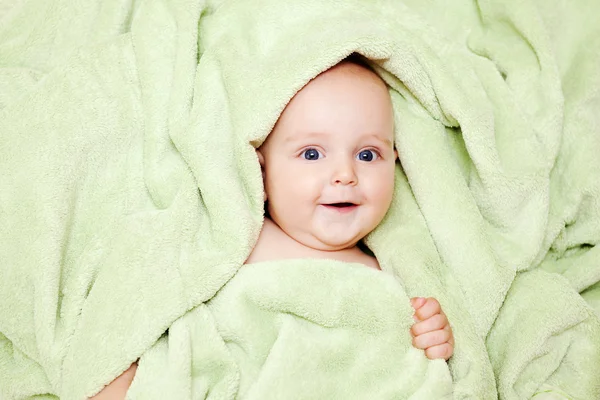 Caucasiano menino coberto com toalha verde alegremente sorri para c — Fotografia de Stock