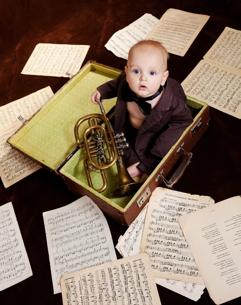 Caucasien bébé garçon joue avec trompette entre feuilles avec musica Image En Vente