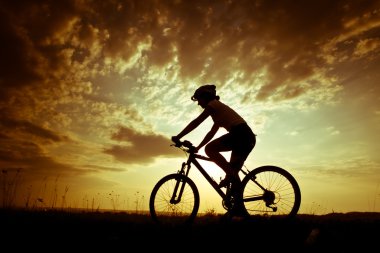 Gün batımında çayırda bisikletli kız.