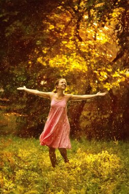 güzel bir gün batımı sırasında yaz yağmur altında genç ve güzel kadın