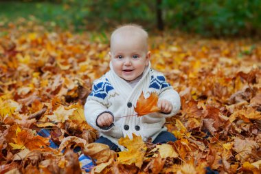 Kabaklar sonbahar Park arasında örme kazaklı çocuk oturur