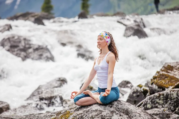 stock image Young woman is practicing yoga at mountain river