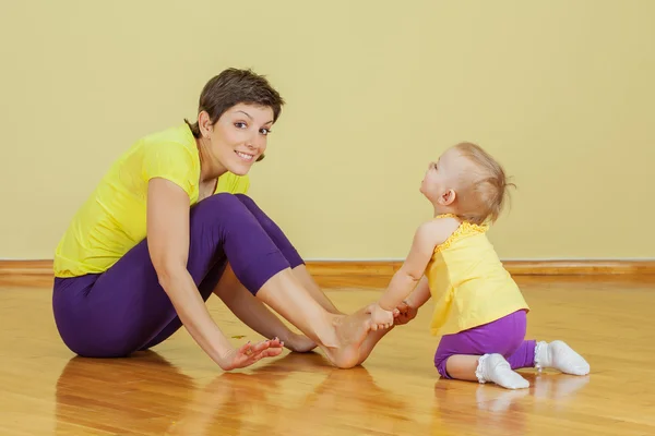 Madre hacer ejercicios físicos con su hija en casa — Foto de Stock