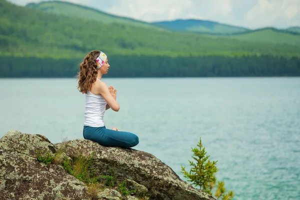 Ung kvinna utövar yoga på fjällsjö — Stockfoto