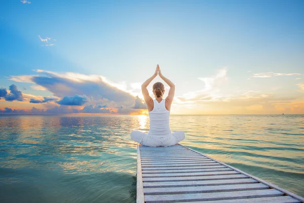 Kaukasisk kvinna utövar yoga på stranden — Stockfoto