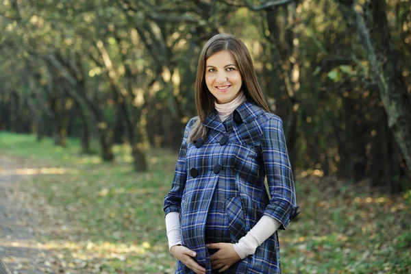 Glada gravida kvinna i parken — Stockfoto