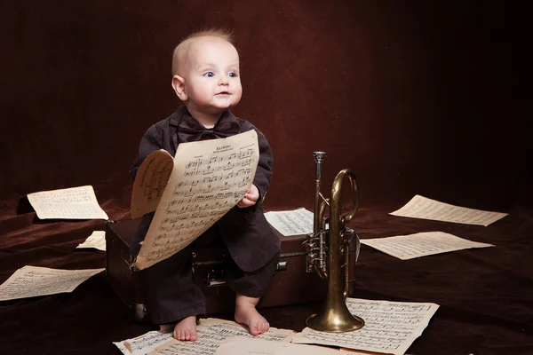 Caucásico bebé niño juega con trompeta entre sábanas con música —  Fotos de Stock