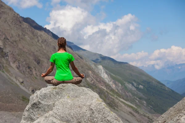 Mujer joven está practicando yoga en las altas montañas — Foto de Stock