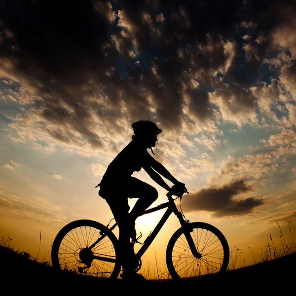 Biker-Mädchen bei Sonnenuntergang auf der Wiese — Stockfoto