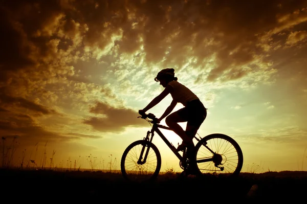 Biker-Mädchen bei Sonnenuntergang auf der Wiese — Stockfoto