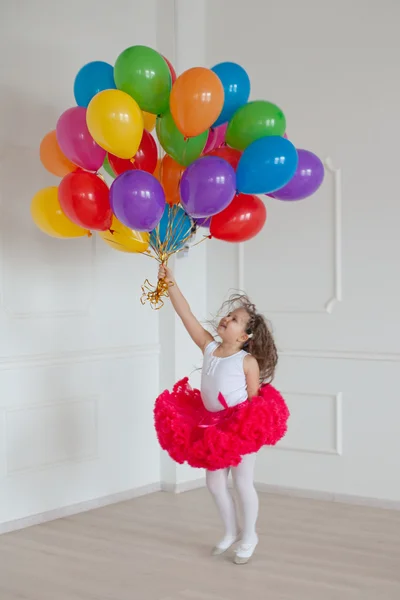 Kleines Mädchen spielt im Studio mit bunten Luftballons — Stockfoto