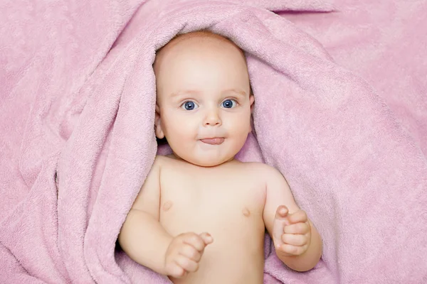 Caucasian baby boy covered with green towel joyfully smiles at c — Stock Photo, Image