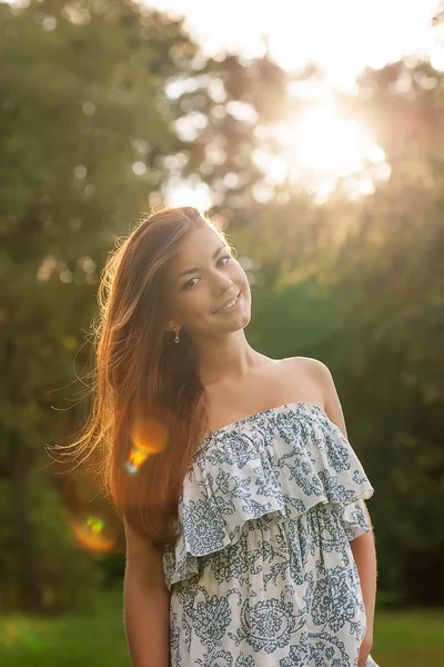 Piękna młoda kobieta w sukni w ogrodzie na zachód słońca — Zdjęcie stockowe
