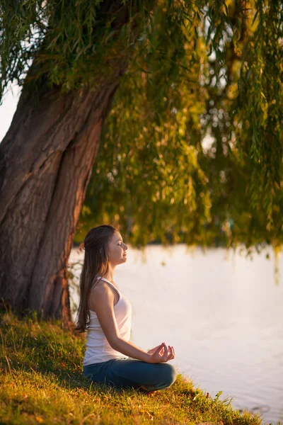 Kaukasisk kvinna utövar yoga på sjön — Stockfoto