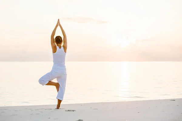 Mujer caucásica practicando yoga en la orilla del mar — Foto de Stock