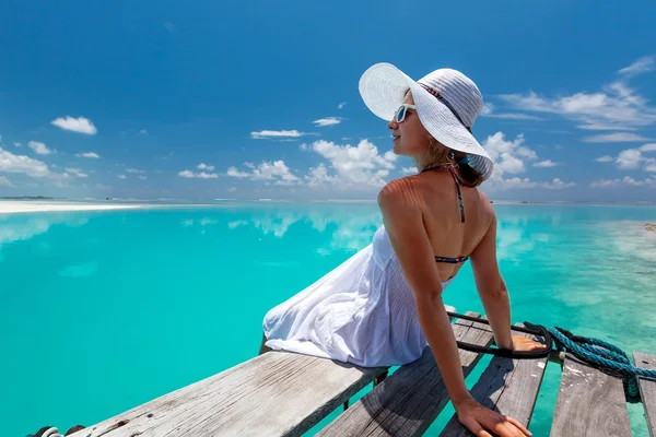 Kaukasische vrouw vindt rest op houten pier tot Indische Oceaan — Stockfoto